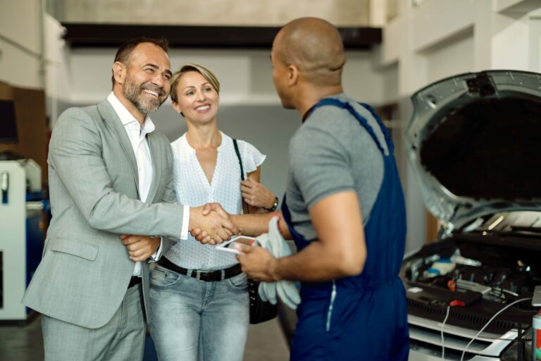 happy-couple-greeting-their-mechanic-auto-repair-shop-min